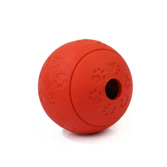 Red treat dispensing dog ball with paw print texture and round treat opening