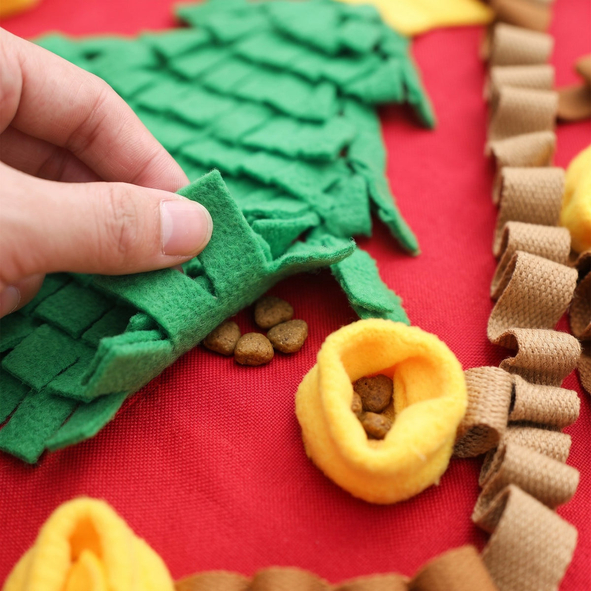 Kibble hidden under the fleece fringe and in a ring pocket of the Christmas tree snuffle mat